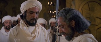 Movie still from “The Message” (1976), directed by Moustapha Akkad – A group of men standing next to each other in a room; Medium shot, Over the shoulder angle