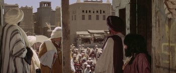 Movie still from “The Message” (1976), directed by Moustapha Akkad – A group of people gathered in the middle of the street; Wide shot, Over the shoulder angle