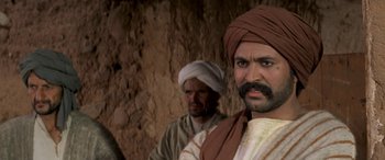 Movie still from “The Message” (1976), directed by Moustapha Akkad – A man with a beard and a turban is standing next to another man with a beard; Close Up shot, Over the shoulder angle