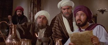 Movie still from “The Message” (1976), directed by Moustapha Akkad – A group of men sitting next to each other in a room; Medium shot, Over the shoulder angle