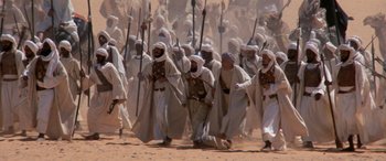 Movie still from “The Message” (1976), directed by Moustapha Akkad – A large group of men in white robes marching in the desert; Wide shot, High angle