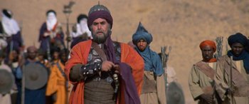 Movie still from “The Message” (1976), directed by Moustapha Akkad – A man in an orange and purple outfit and a man in a blue turban; Medium shot, Low angle