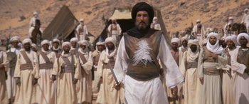 Movie still from “The Message” (1976), directed by Moustapha Akkad – A group of men standing next to each other in a desert; Medium shot, Low angle