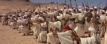 Movie still from “The Message” (1976), directed by Moustapha Akkad – A group of men in white robes and white hats are holding arrows; Wide shot, High angle