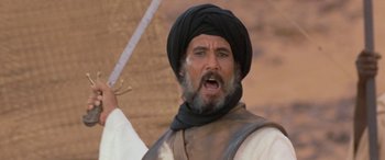 Movie still from “The Message” (1976), directed by Moustapha Akkad – A man with a beard and a turban is holding a sword; Close Up shot, Low angle