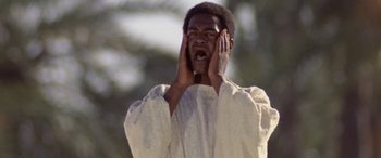 Movie still from “The Message” (1976), directed by Moustapha Akkad – A man in a white shirt is holding his hands to his face; Close Up shot, Low angle