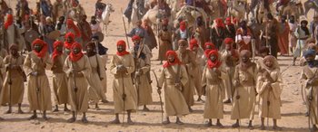 Movie still from “The Message” (1976), directed by Moustapha Akkad – A group of men in long robes and red hats; Wide shot, High angle