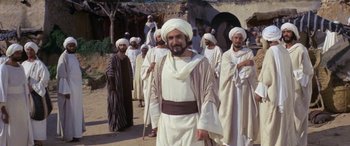 Movie still from “The Message” (1976), directed by Moustapha Akkad – A group of men standing next to each other on a street; Medium shot, Over the shoulder angle