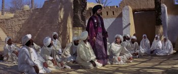 Movie still from “The Message” (1976), directed by Moustapha Akkad – A group of men sitting on the ground next to each other; Wide shot, High angle