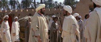Movie still from “The Message” (1976), directed by Moustapha Akkad – A group of men standing next to each other on top of a dirt field; Medium shot, Over the shoulder angle