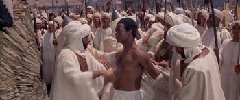 Movie still from “The Message” (1976), directed by Moustapha Akkad – A group of men in white robes are standing in a crowd; Medium shot, High angle