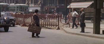 Movie still from “The Moment of Truth” (1965), directed by Francesco Rosi – A man walking down the street carrying a suitcase; Wide shot, High angle