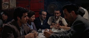Movie still from “The Moment of Truth” (1965), directed by Francesco Rosi – A group of men sitting at a table with drinks; Medium shot, High angle