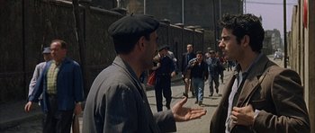 Movie still from “The Moment of Truth” (1965), directed by Francesco Rosi – A group of people walking down a street; Medium shot, Over the shoulder angle