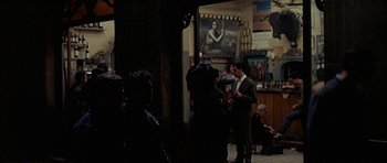 Movie still from “The Moment of Truth” (1965), directed by Francesco Rosi – A group of people standing in a room; Wide shot, Over the shoulder angle