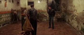 Movie still from “The Moment of Truth” (1965), directed by Francesco Rosi – Two men standing on a tiled floor in an old building; Wide shot, Over the shoulder angle