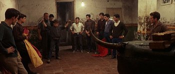 Movie still from “The Moment of Truth” (1965), directed by Francesco Rosi – A group of men standing around in a room; Wide shot, High angle