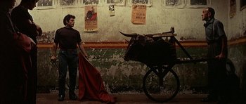 Movie still from “The Moment of Truth” (1965), directed by Francesco Rosi – A man standing in front of a cart with a bull on it; Wide shot, Low angle