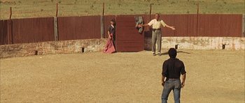 Movie still from “The Moment of Truth” (1965), directed by Francesco Rosi – Two men and a woman are in a fenced in area; Wide shot, High angle