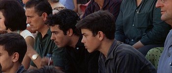 Movie still from “The Moment of Truth” (1965), directed by Francesco Rosi – Two young men sitting next to each other in front of a group of people; Close Up shot, High angle