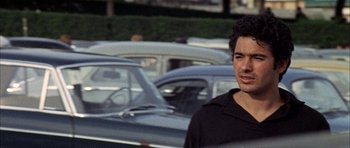 Movie still from “The Moment of Truth” (1965), directed by Francesco Rosi – A man standing in front of a row of parked cars; Close Up shot, Over the shoulder angle