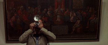 Movie still from “The Moment of Truth” (1965), directed by Francesco Rosi – A man taking a picture in front of a painting; Medium shot, Low angle