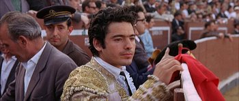 Movie still from “The Moment of Truth” (1965), directed by Francesco Rosi – A man in a suit and tie sitting in front of a group of people; Close Up shot, Low angle