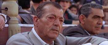 Movie still from “The Moment of Truth” (1965), directed by Francesco Rosi – An older man in a gray suit is looking at the camera; Close Up shot, Low angle