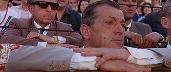 Movie still from “The Moment of Truth” (1965), directed by Francesco Rosi – An older man sitting next to a group of people; Close Up shot, Low angle