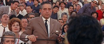 Movie still from “The Moment of Truth” (1965), directed by Francesco Rosi – An older man in a brown suit holding a pair of glasses; Medium shot, Low angle