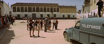 Movie still from “The Moment of Truth” (1965), directed by Francesco Rosi – A group of people standing in front of an old car; Wide shot, High angle