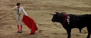 Movie still from “The Moment of Truth” (1965), directed by Francesco Rosi – A man in a red cape is trying to block a bull; Wide shot, High angle