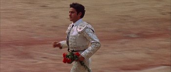Movie still from “The Moment of Truth” (1965), directed by Francesco Rosi – A man in a white suit holding a bouquet of roses; Medium shot, High angle