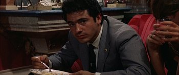 Movie still from “The Moment of Truth” (1965), directed by Francesco Rosi – A man sitting at a table in a suit and tie; Close Up shot, High angle