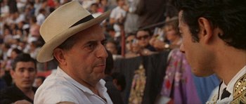Movie still from “The Moment of Truth” (1965), directed by Francesco Rosi – A man wearing a straw hat in front of a group of onlookers; Close Up shot, High angle