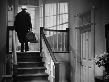 Movie still from “The More the Merrier” (1943), directed by George Stevens – A man walking down the stairs holding a bag; Wide shot, Low angle