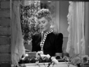 Movie still from “The More the Merrier” (1943), directed by George Stevens – An old black and white photo of a woman looking at a tablet; Medium shot, High angle