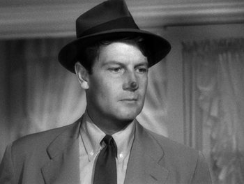 Movie still from “The More the Merrier” (1943), directed by George Stevens – A black and white photo of a man wearing a suit and a hat; Close Up shot, Low angle