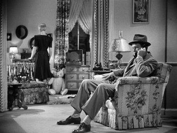 Movie still from “The More the Merrier” (1943), directed by George Stevens – A man sitting on a chair talking on the phone; Wide shot, High angle