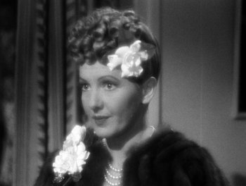 Movie still from “The More the Merrier” (1943), directed by George Stevens – An old photo of a woman with flowers in her hair; Close Up shot, Over the shoulder angle