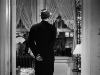 Movie still from “The More the Merrier” (1943), directed by George Stevens – A black and white photo of a man looking out of a window; Medium shot, Over the shoulder angle