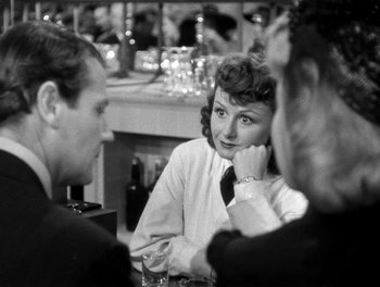Movie still from “The More the Merrier” (1943), directed by George Stevens – A woman sitting at a table talking to two men; Medium shot, Over the shoulder angle