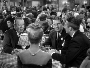 Movie still from “The More the Merrier” (1943), directed by George Stevens – A black and white photo of people sitting at a table; Medium shot, Over the shoulder angle