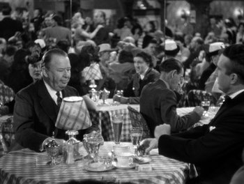 Movie still from “The More the Merrier” (1943), directed by George Stevens – A black and white photo of people sitting at tables; Medium shot, High angle