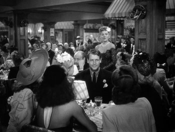 Movie still from “The More the Merrier” (1943), directed by George Stevens – A black and white photo of people sitting at a table; Medium shot, Over the shoulder angle