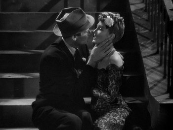 Movie still from “The More the Merrier” (1943), directed by George Stevens – A man and a woman sitting on a set of stairs; Medium shot, Overhead angle