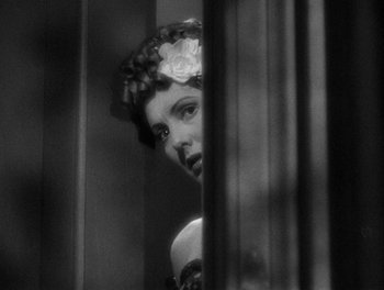 Movie still from “The More the Merrier” (1943), directed by George Stevens – A black - and - white photo of a woman with a flower in her hair; Close Up shot, Over the shoulder angle