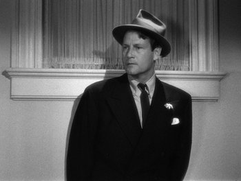 Movie still from “The More the Merrier” (1943), directed by George Stevens – A black and white photo of a man wearing a suit and hat; Close Up shot, Low angle