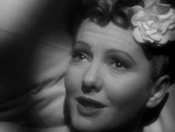 Movie still from “The More the Merrier” (1943), directed by George Stevens – An old black and white photo of a woman with a flower in her hair; Close Up shot, High angle