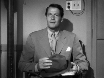 Movie still from “The More the Merrier” (1943), directed by George Stevens – A black and white photo of a man wearing a suit and tie; Close Up shot, High angle